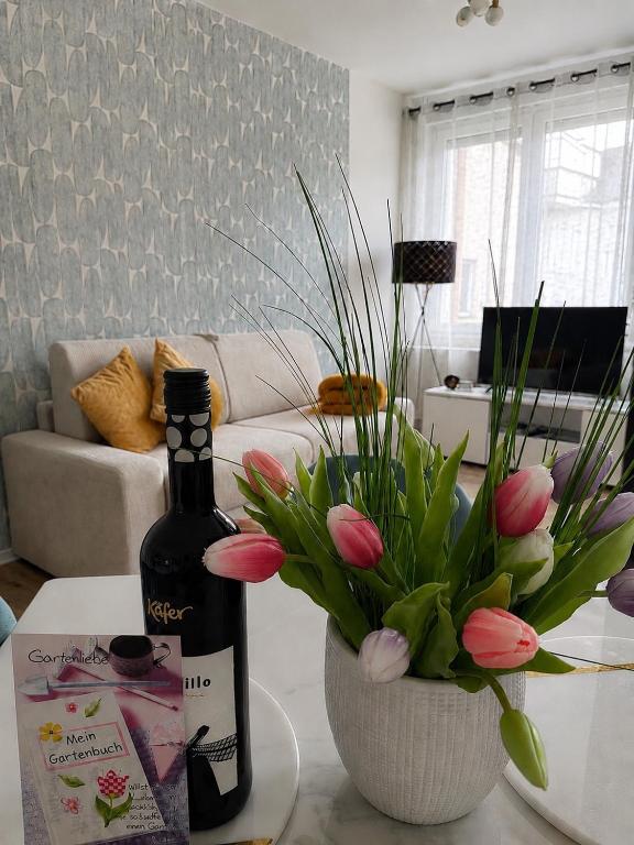 Ferienwohnung Rehn 1 في باد كيسينغن: زجاجة نبيذ ومزهرية زهور على طاولة