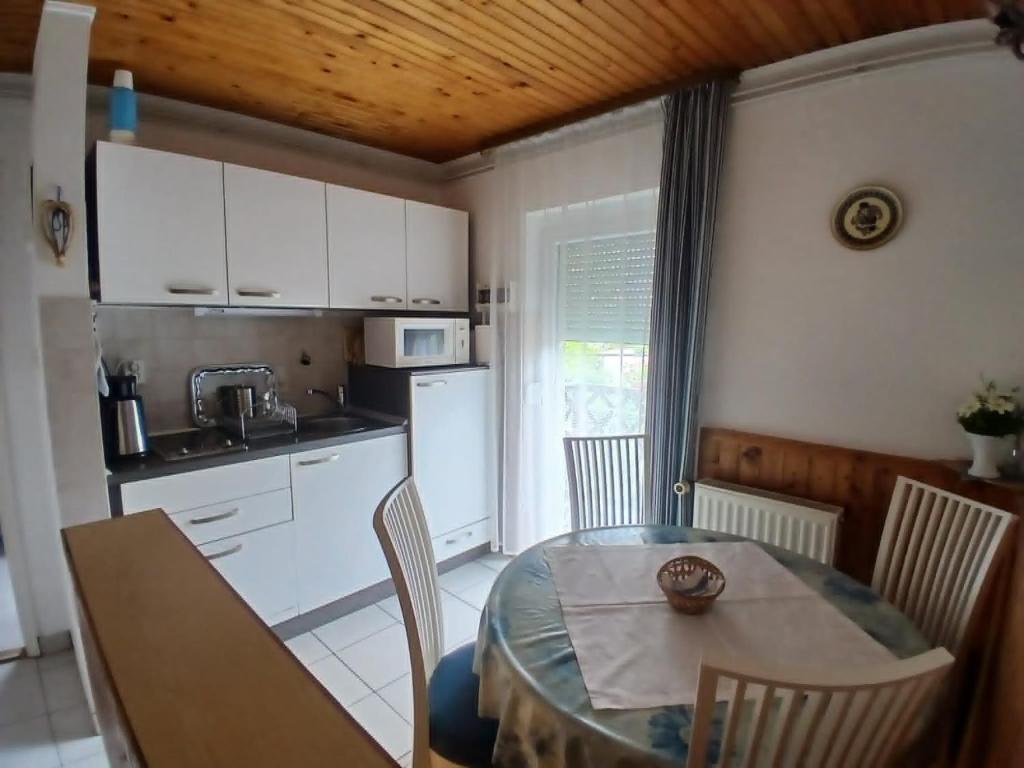 a kitchen with a table and chairs and a kitchen with white cabinets at Czanek Apartman in Komárom
