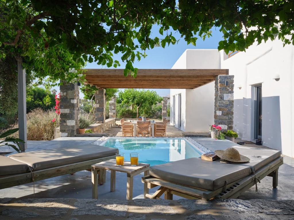 a swimming pool in a backyard with a table and a patio at SeaSalt Dream Villa,Santa Maria 5 min from Naousa in Santa Marina