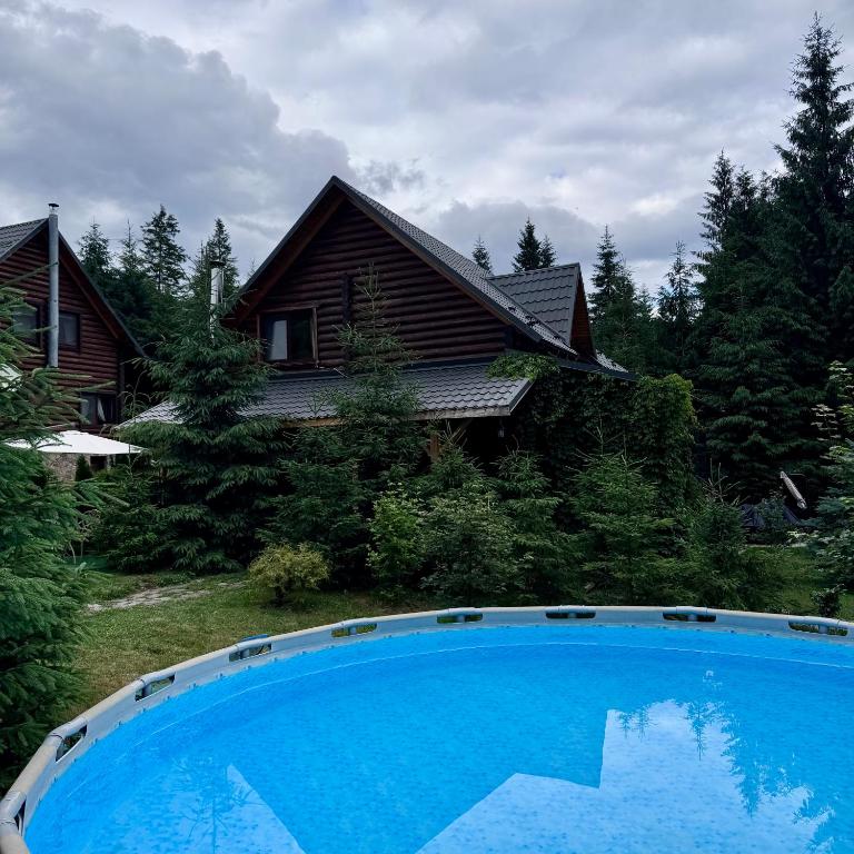 a large blue swimming pool in front of a house at Cottage Lavanda окремий котедж з каміном in Bukovel