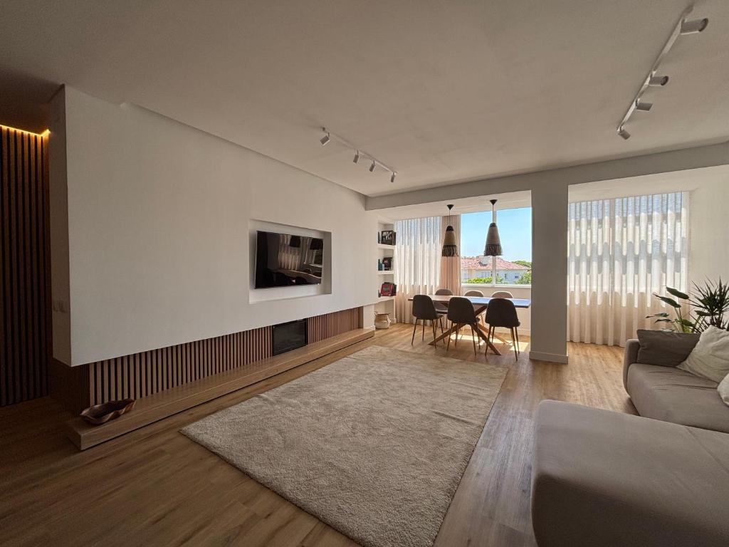 a living room with a couch and a tv on a wall at Vila apartment, free parking in Cascais