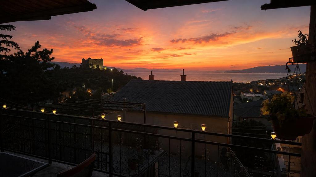 a sunset over a city with a castle on a hill at Apartments Ivka & Garden in Senj