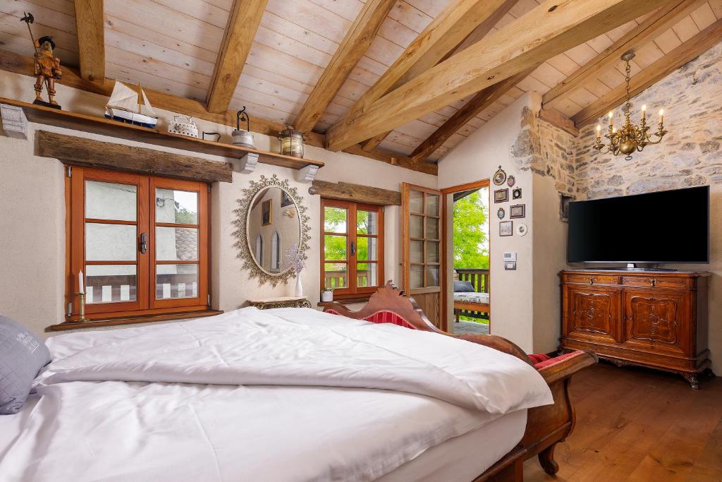 a bedroom with a large bed and a flat screen tv at Krasna Hiška - Authentic Heritage Home in Sežana