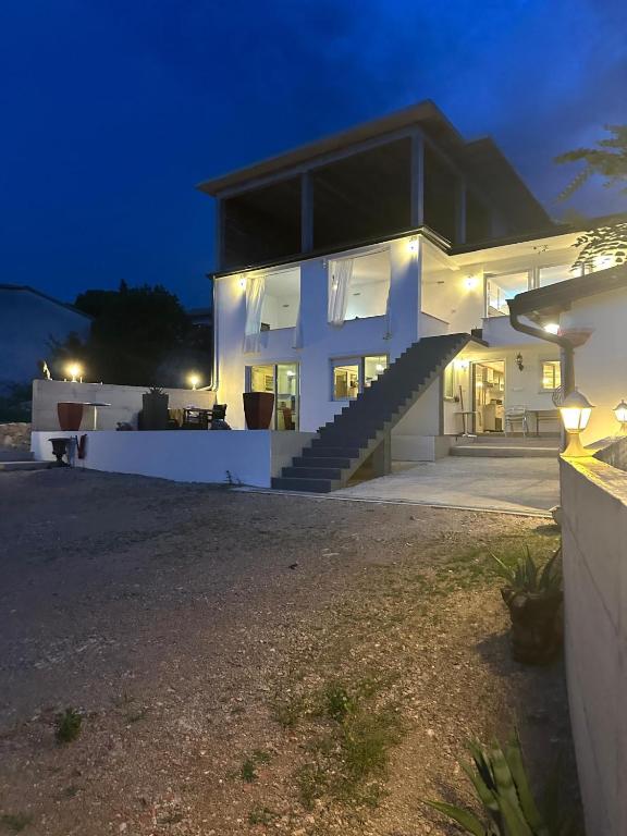 a white house with a staircase in front of it at night at Irma Haus in Jadranovo