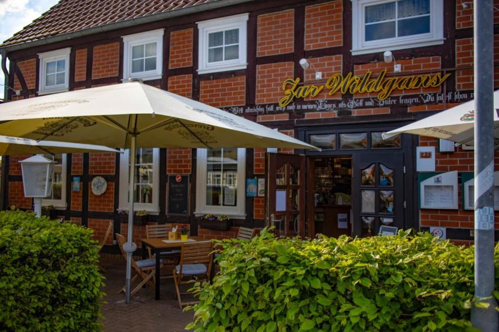 ein Tisch mit einem Sonnenschirm vor einem Gebäude in der Unterkunft Restaurant und Pension Zur Wildgans in Arendsee