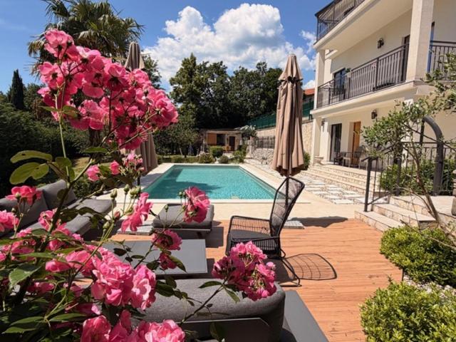 a house with a swimming pool and pink flowers at Luxury Kvarner Park Villa with garden and large RGB private pool in Kastav