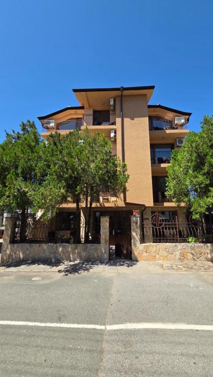 a tall building with trees in front of a street at D House in Chernomorets