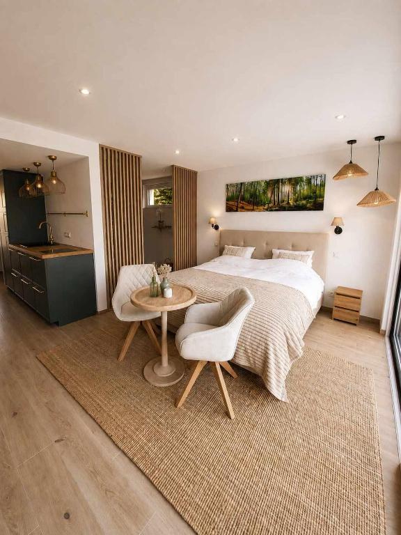 a bedroom with a large bed and a table at Le Cocon, Jacuzzi privé Spa Francorchamps in Spa