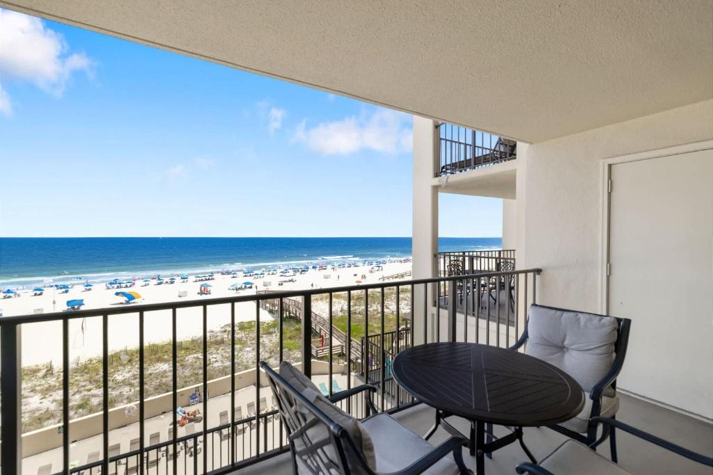 a balcony with a table and chairs and the beach at Beachfront Paradise at Phoenix II 2046 in Orange Beach