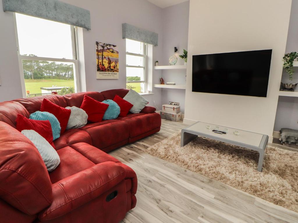 a living room with a red couch and a flat screen tv at Sugar Loft in Wigton