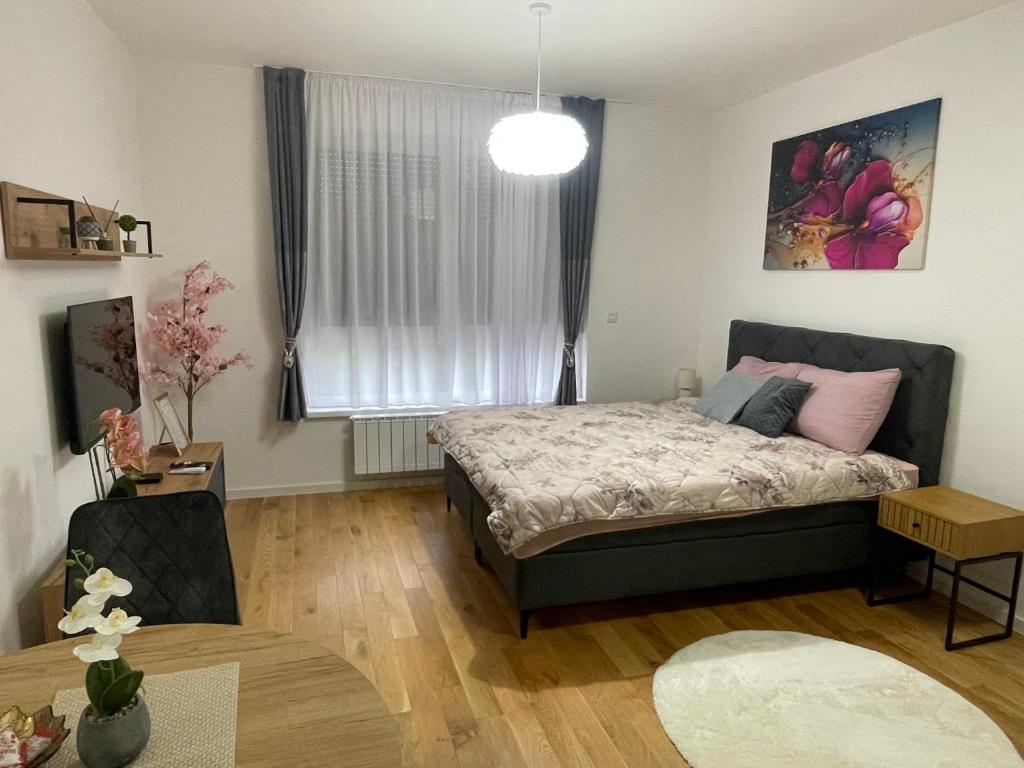 a bedroom with a bed and a table at Orhideja 075 in Tuzla