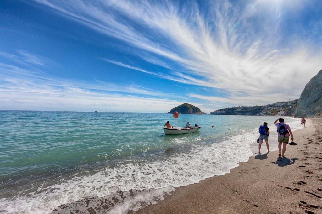 a group of people walking on a beach with a boat at Villa Mattera - Sea - Hot Springs - Private Parking in Barano d'Ischia