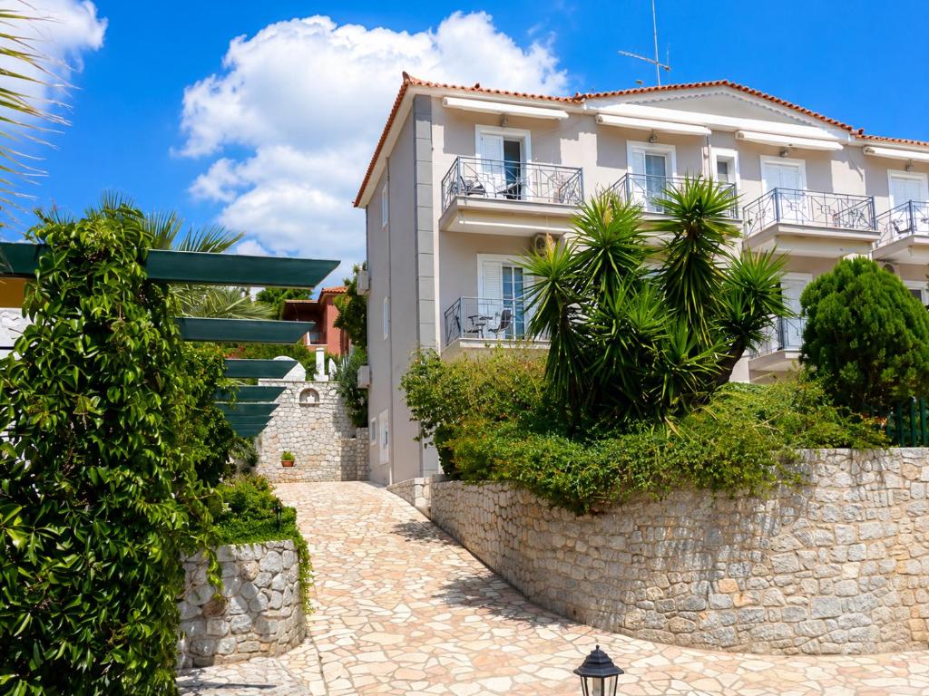 a white house with a stone wall and trees at Louis' apartment with view in Gythio