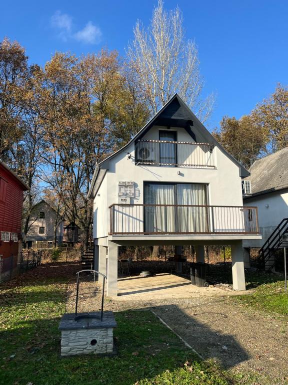 a white house with a balcony and a yard at Officium P47 in Rakamaz