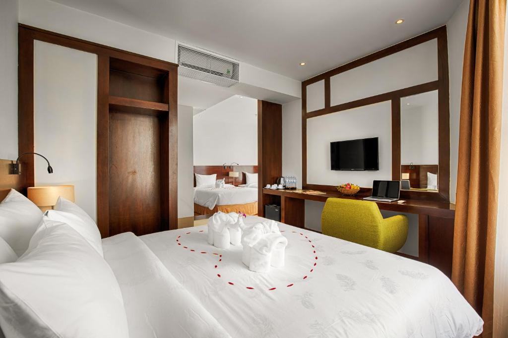 a bedroom with a large white bed with a desk at Sofia Suite Hotel Danang in Da Nang