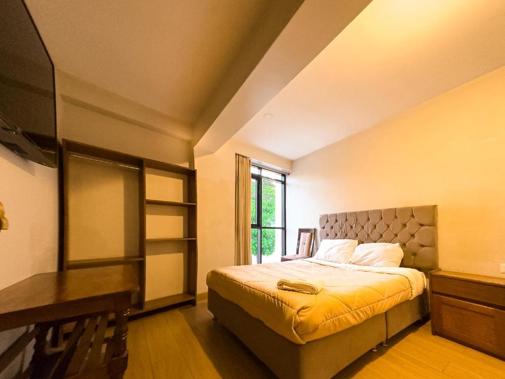 a bedroom with a bed and a desk and a window at Hotel Qoyllur urcos in Urcos