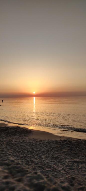 a sunset over the ocean with a sandy beach at Willa Madi in Grzybowo