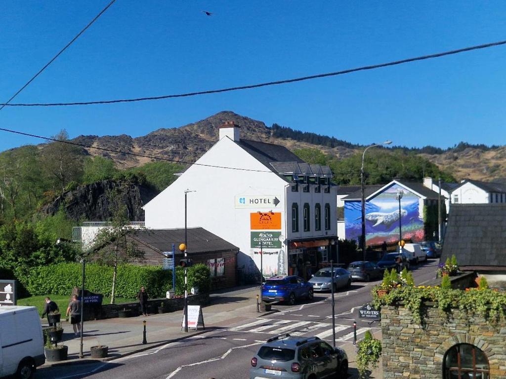 a town with cars parked on a street with a mountain at Glengarriff Hostel in Glengarriff