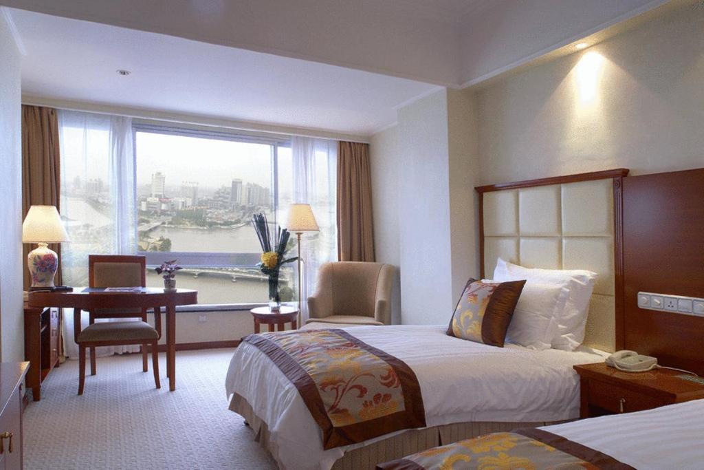 a hotel room with two beds and a desk and a window at Citic Ningbo International Hotel in Ningbo