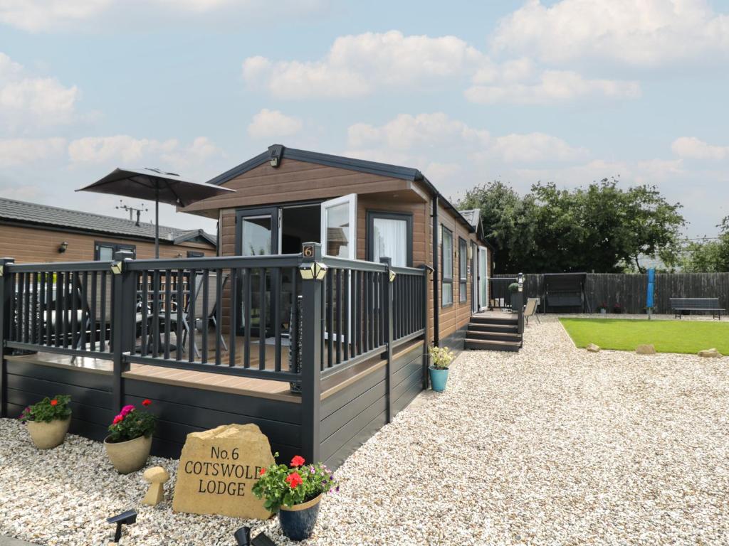 a tiny house with a porch and a patio at The Cotswold Holiday Lodge in Evesham