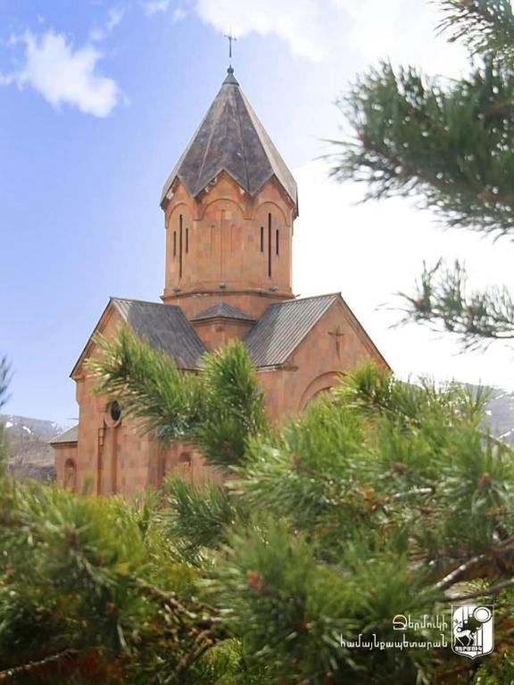 an old church with a tower on top of some trees at Уютный дом в Джермуке in Jermuk