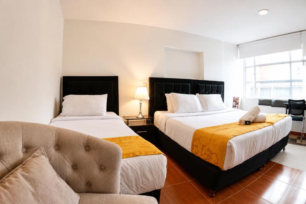 a hotel room with two beds and a couch at House Studio Hotel in Bogotá
