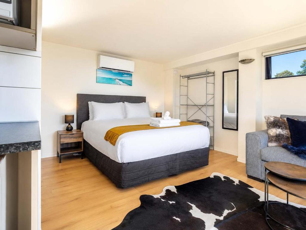 a bedroom with a bed and a couch and a table at Aqua Sands #2 - Stay Waiheke in Oneroa