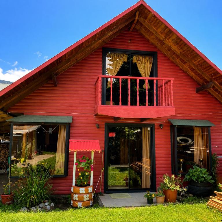 a red house with a balcony and a window at Refugio Barbara Coñaripe in Coñaripe