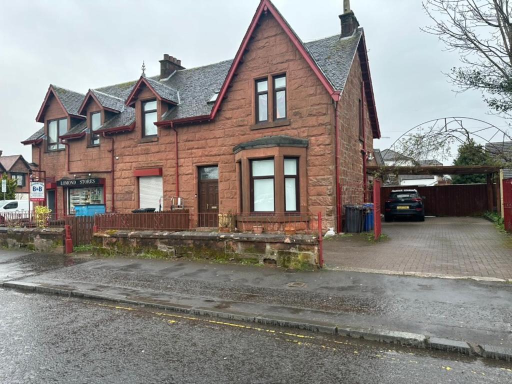 a red brick house with a driveway in front of it at Lomond Villa in Balloch
