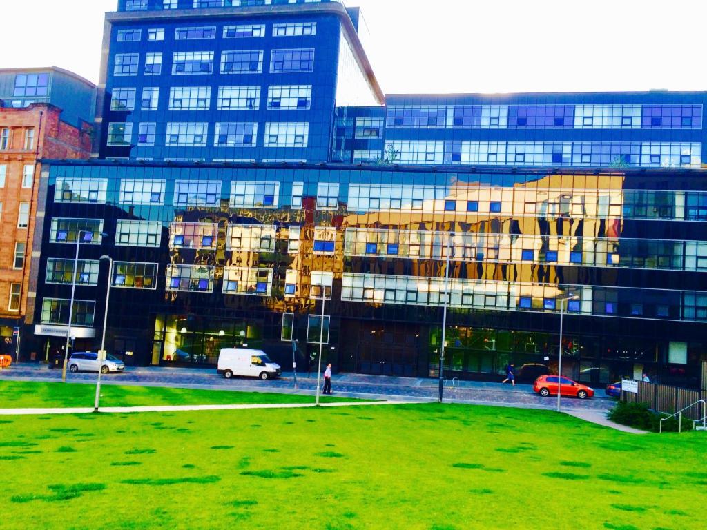 a large building with a grass field in front of it at Glasgow City Center Flat with Parking in Glasgow