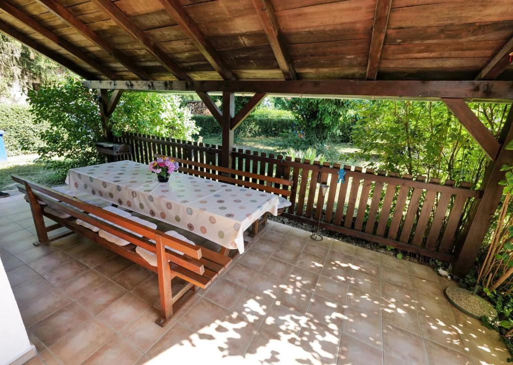 a table and bench under a wooden pergola at Kuća za odmor Na jezeru, Šoderica - Fenced Yard & Pet friendly holidayhouse in Legrad