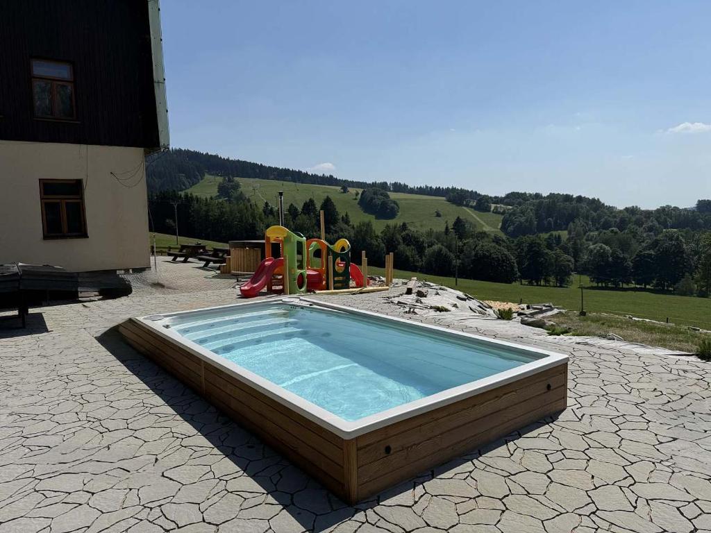 a swimming pool with a slide and a playground at Chalupa Šťastný kopec in Deštné v Orlických horách