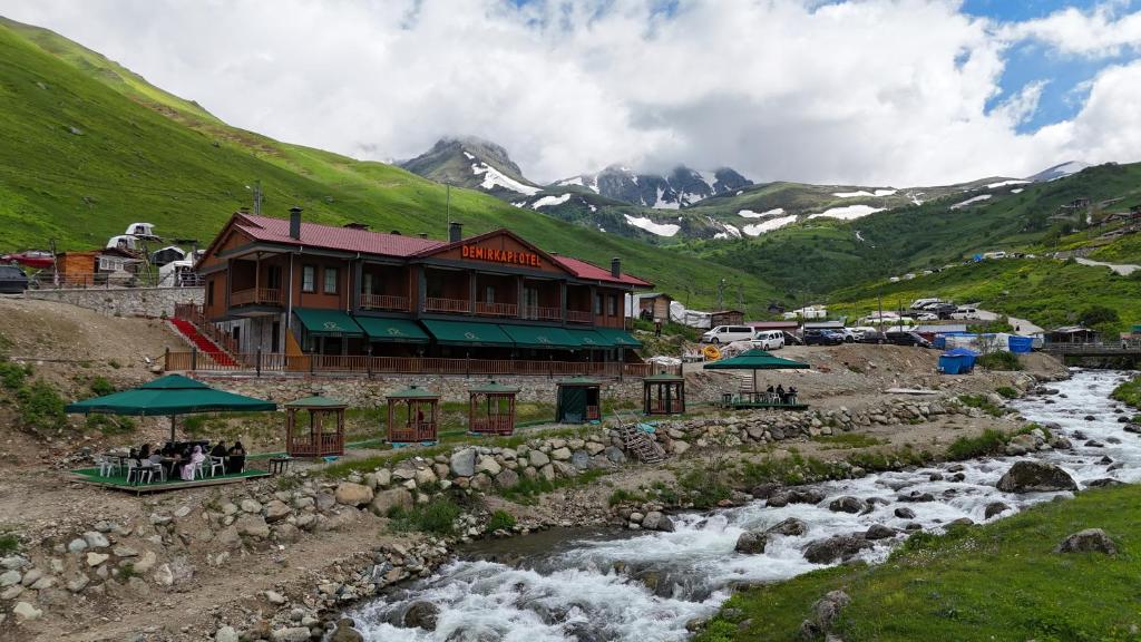 a building next to a river next to a mountain at Demirkapı Otel in Uzungöl