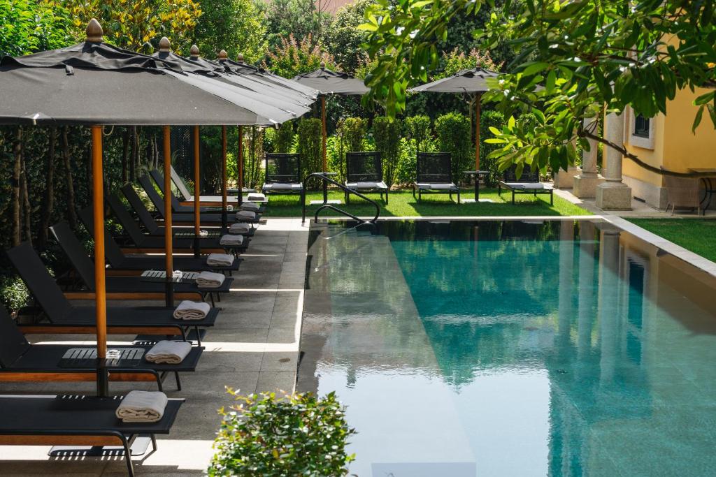 a swimming pool with lounge chairs and umbrellas at Palacete Severo in Porto
