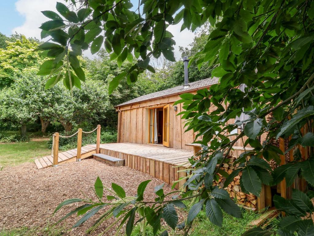 a wooden cabin with a wooden porch in a garden at Brambly Cabin in Crediton