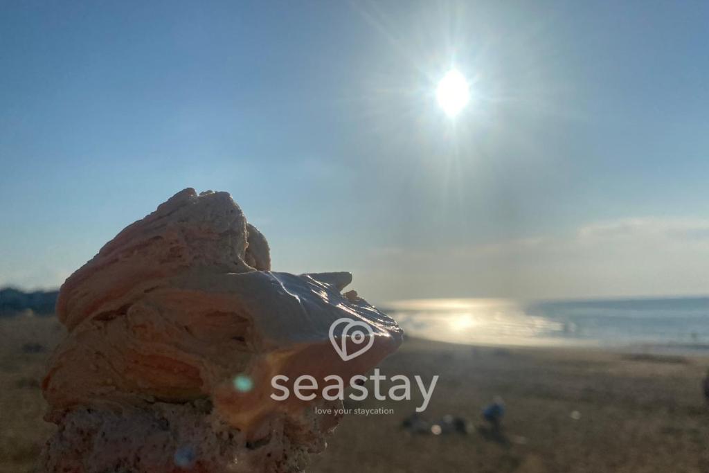 a rock on a beach with the sun in the background at Sea Farm Stays in Broadstairs