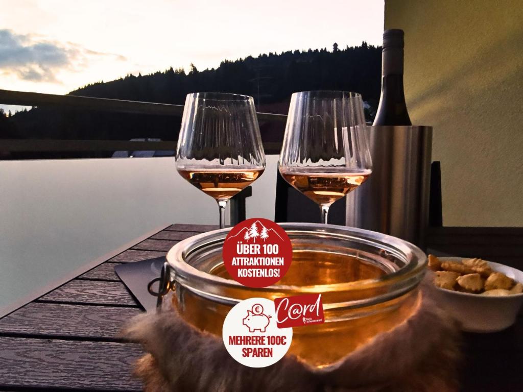 a table with two glasses of wine and a bowl of food at FeWo Schwarzwaldschick Feldberg I Bergurlaub I Balkon I Whirlwanne I Tiefgarage I HochschwarzwaldCard inkl in Feldberg