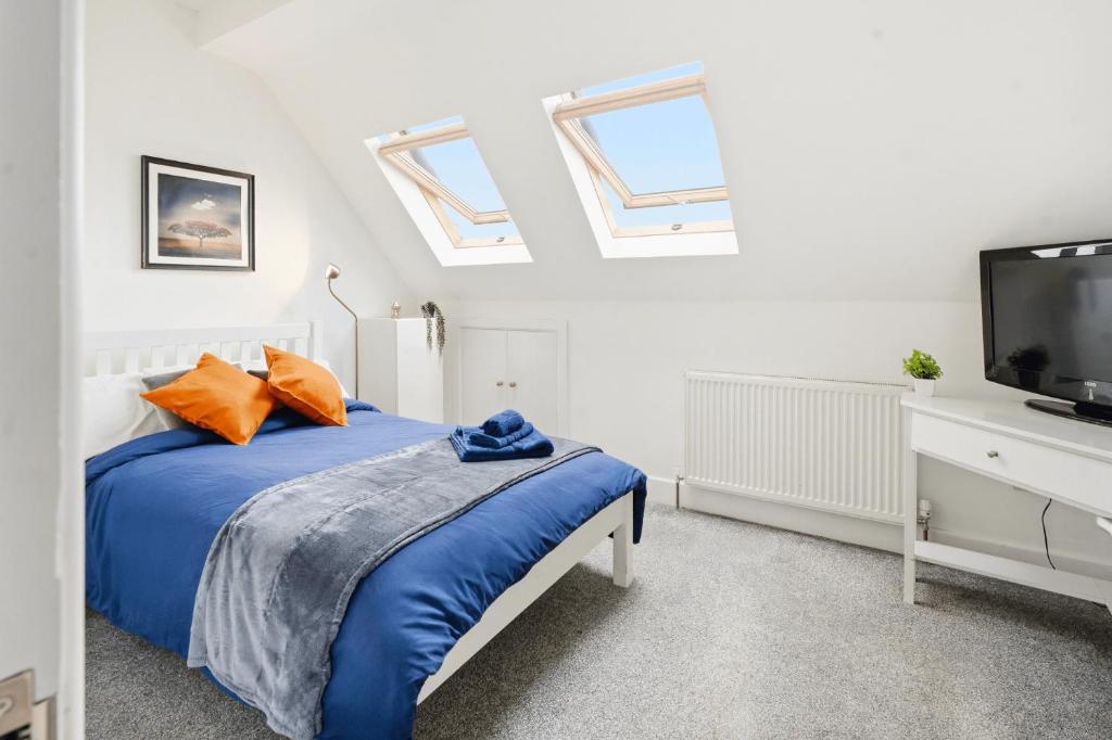 a bedroom with a bed with blue sheets and a tv at Sky View En-Suite in Egham