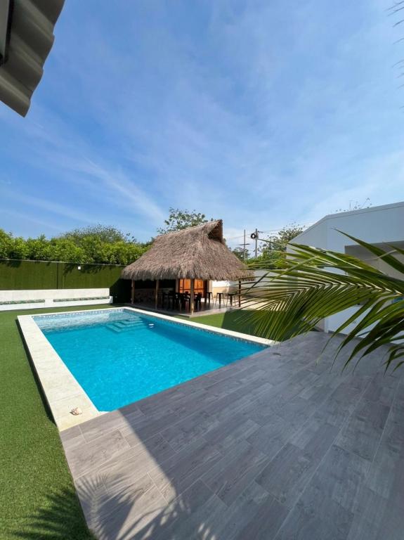 a villa with a swimming pool and a thatch hut at Guantalamera Resort in Tubará