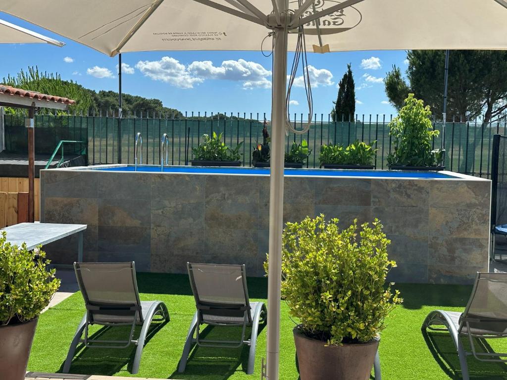 a patio with chairs and an umbrella and a pool at Las Casas de Pecheye in Bocigas