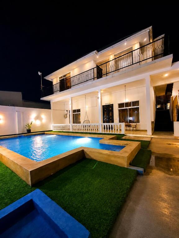 a swimming pool in front of a house at night at Nanaa Hotel in Nungwi