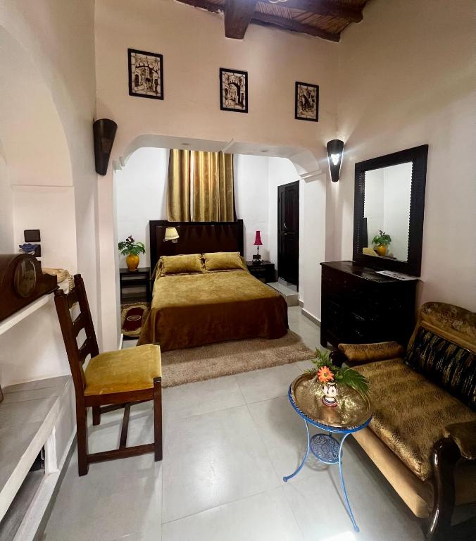 a bedroom with a bed and a couch and a table at Riad Le Lieu in Tiznit