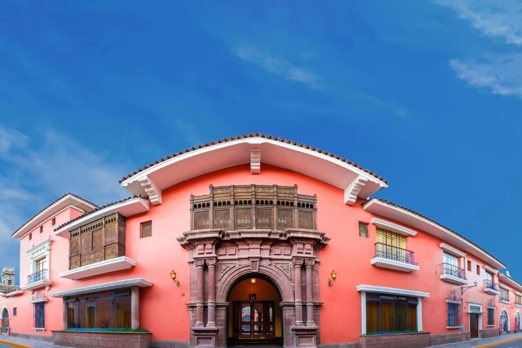 a pink building with a balcony on a street at DM Hoteles Ayacucho in Ayacucho