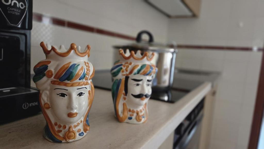 two vases with faces on them sitting on a counter at Marinello house in Oliveri