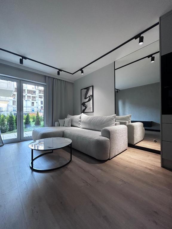a living room with a white couch and a table at Apartament z Tarasem Parking Smart TV Wi-Fi in Sosnowiec