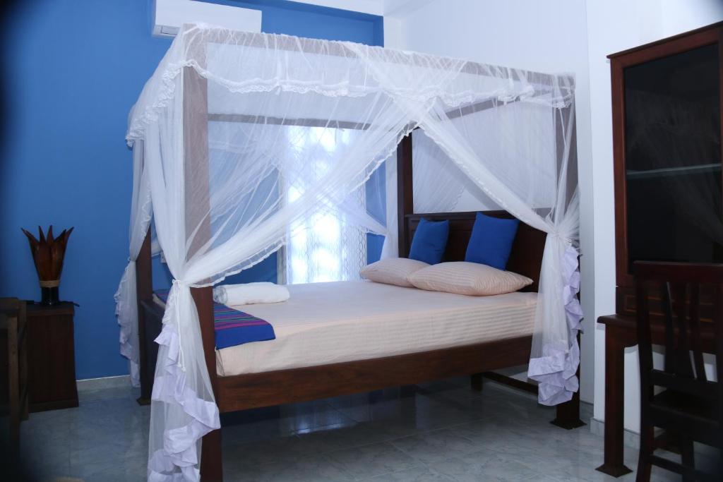 a bedroom with a canopy bed with a window at Akurala Beach Park in Hikkaduwa