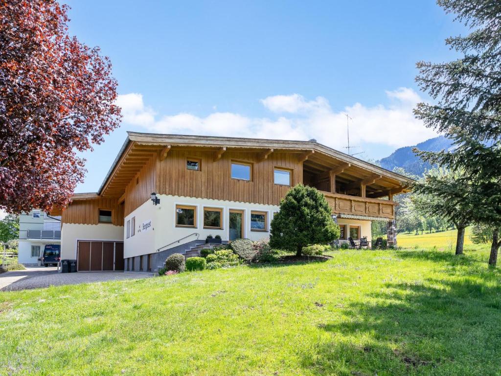 a large wooden house with a grassy yard at Das Bergnest Salvenblick in Söll