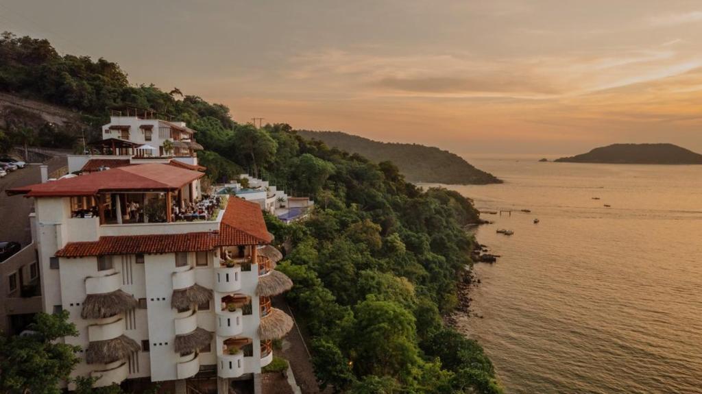 a building on a hill next to a body of water at Pacífica Grand Zihuatanejo in Zihuatanejo