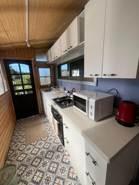 a kitchen with a microwave and a stove top oven at Cabaña en Rafael in Tomé