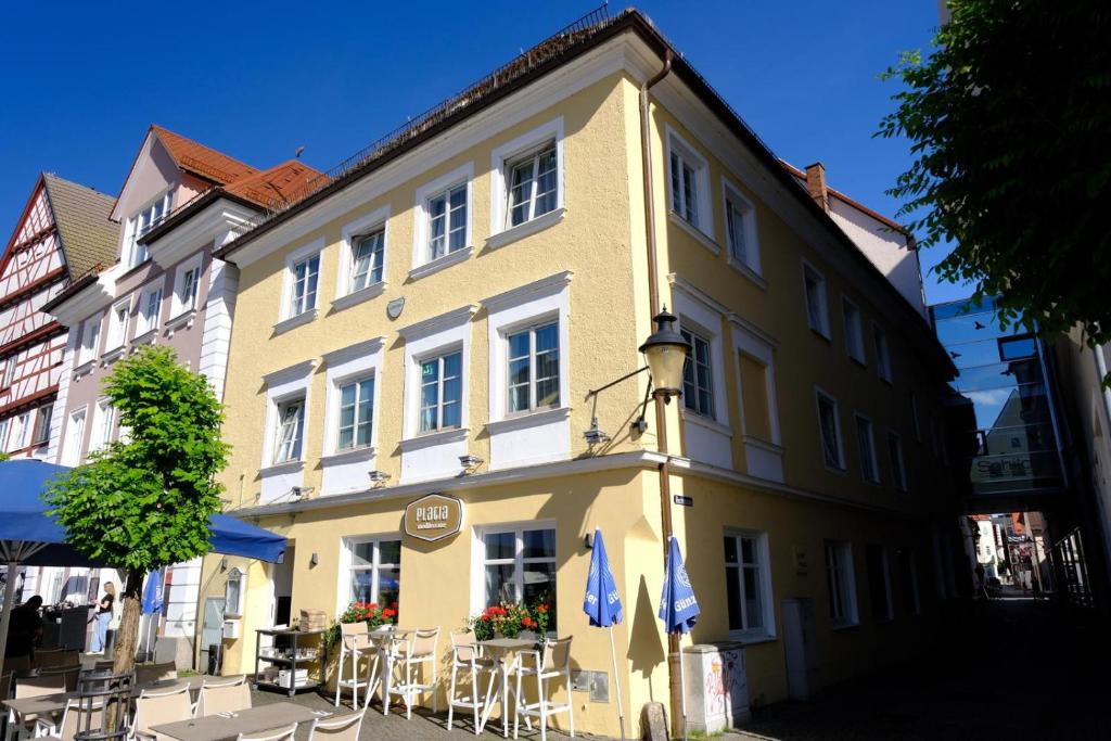 a yellow building with tables and chairs in front of it at Hotel - PLATIA in Günzburg